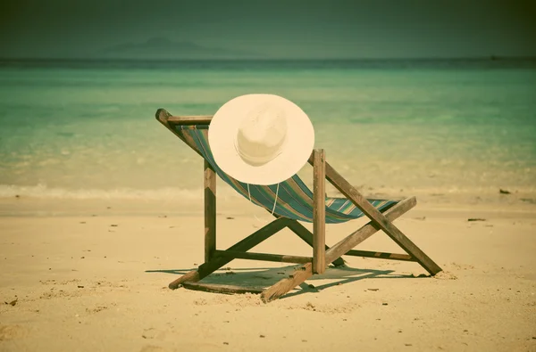 Exotic beach holiday background with white hate on beach chair — Stock Photo, Image