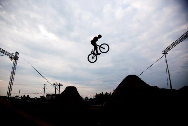 Günbatımı karşı bir bmx bisiklet ile bir sıçrama yapan bir erkek silüeti 