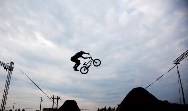 Günbatımı karşı bir bmx bisiklet ile bir sıçrama yapan bir erkek silüeti 