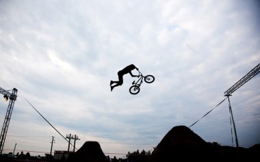 Günbatımı karşı bir bmx bisiklet ile bir sıçrama yapan bir erkek silüeti 