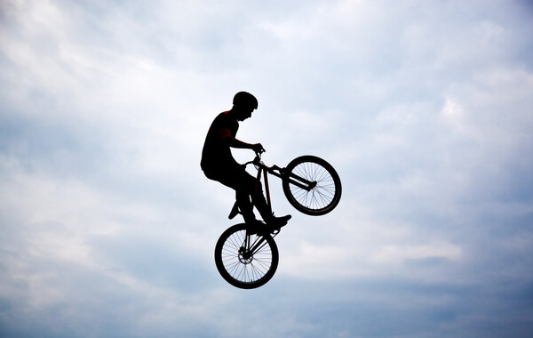 Silhouette of a man doing a jump with a bmx bike against sunset 