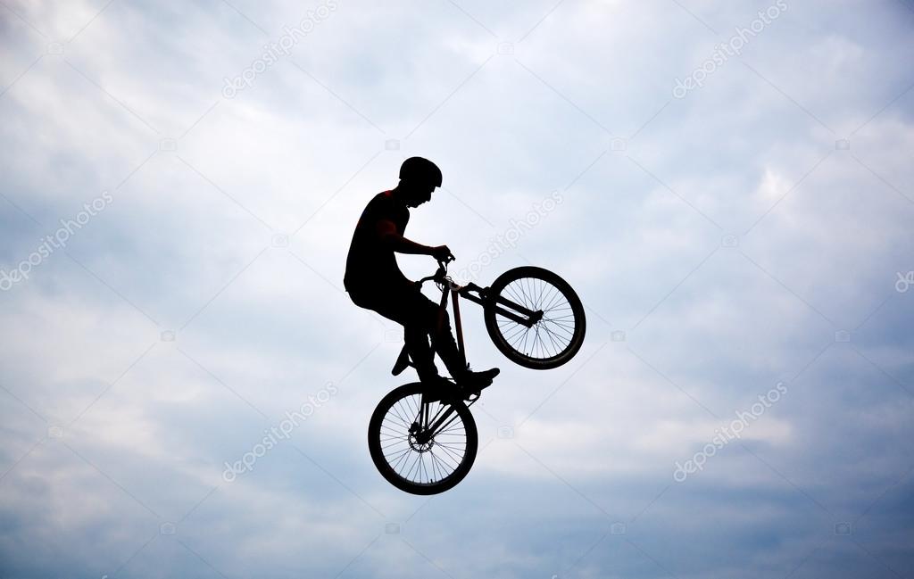 Silhouette of a man doing a jump with a bmx bike against sunset — Stock