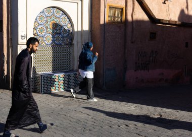 MARRAKESH, MOROCCO - 4 Aralık 2025: Yerliler ve turistler, Unesco dünya mirasının bir parçası olan Marakeş eski Medine sokaklarında ve geleneksel pazarlarda günlük işlerine devam ediyorlar