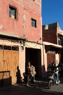 MARRAKESH, MOROCCO - 4 Aralık 2025: Yerliler ve turistler, Unesco dünya mirasının bir parçası olan Marakeş eski Medine sokaklarında ve geleneksel pazarlarda günlük işlerine devam ediyorlar