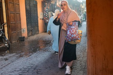 MARRAKESH, MOROCCO - 4 Aralık 2025: Yerliler ve turistler, Unesco dünya mirasının bir parçası olan Marakeş eski Medine sokaklarında ve geleneksel pazarlarda günlük işlerine devam ediyorlar
