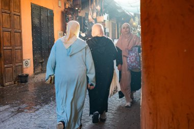 MARRAKESH, MOROCCO - 4 Aralık 2025: Yerliler ve turistler, Unesco dünya mirasının bir parçası olan Marakeş eski Medine sokaklarında ve geleneksel pazarlarda günlük işlerine devam ediyorlar