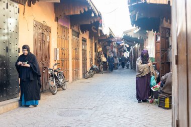 MARRAKESH, MOROCCO - 4 Aralık 2025: Yerliler ve turistler, Unesco dünya mirasının bir parçası olan Marakeş eski Medine sokaklarında ve geleneksel pazarlarda günlük işlerine devam ediyorlar