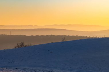 Karlı tepelerin ardında gün batımı