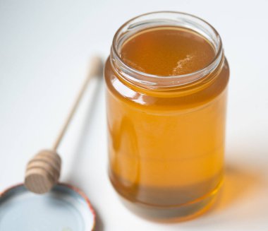 organik bal, ahşap bir kaptan cam bir kavanoza damlıyor.,