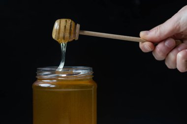 organik bal, ahşap bir kaptan cam bir kavanoza damlıyor.,