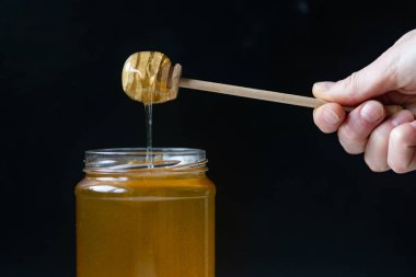 organik bal, ahşap bir kaptan cam bir kavanoza damlıyor.,