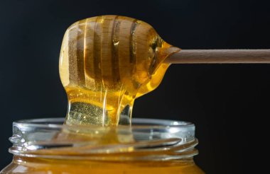 organik bal, ahşap bir kaptan cam bir kavanoza damlıyor.,