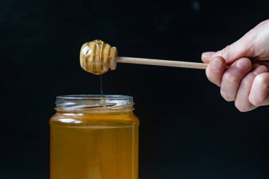 organik bal, ahşap bir kaptan cam bir kavanoza damlıyor.,