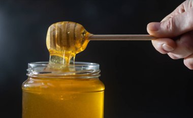 organik bal, ahşap bir kaptan cam bir kavanoza damlıyor.,