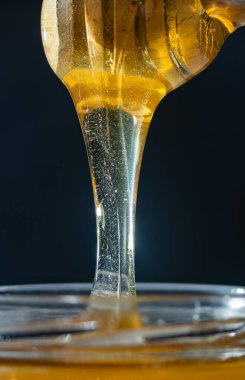 organik bal, ahşap bir kaptan cam bir kavanoza damlıyor.,