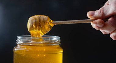 organik bal, ahşap bir kaptan cam bir kavanoza damlıyor.,