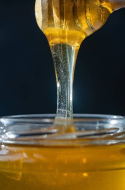 organik bal, ahşap bir kaptan cam bir kavanoza damlıyor.,