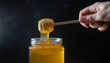 organik bal, ahşap bir kaptan cam bir kavanoza damlıyor.,