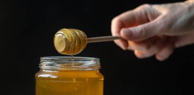 organik bal, ahşap bir kaptan cam bir kavanoza damlıyor.,