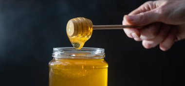 organik bal, ahşap bir kaptan cam bir kavanoza damlıyor.,