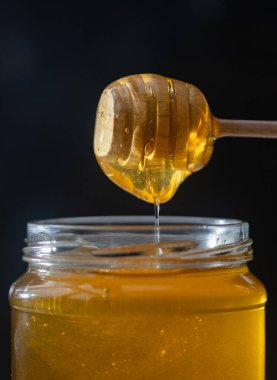 organik bal, ahşap bir kaptan cam bir kavanoza damlıyor.,