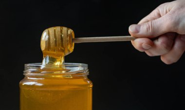 organik bal, ahşap bir kaptan cam bir kavanoza damlıyor.,