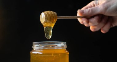 organik bal, ahşap bir kaptan cam bir kavanoza damlıyor.,