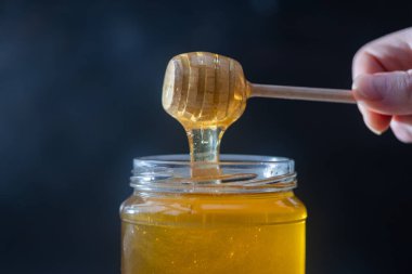 organik bal, ahşap bir kaptan cam bir kavanoza damlıyor.,