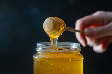 organik bal, ahşap bir kaptan cam bir kavanoza damlıyor.,