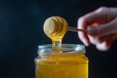 organik bal, ahşap bir kaptan cam bir kavanoza damlıyor.,