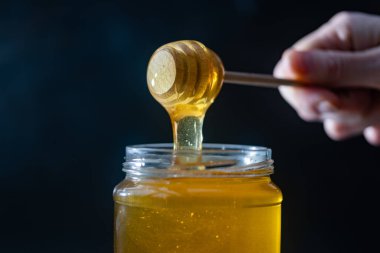 organik bal, ahşap bir kaptan cam bir kavanoza damlıyor.,