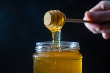 organik bal, ahşap bir kaptan cam bir kavanoza damlıyor.,