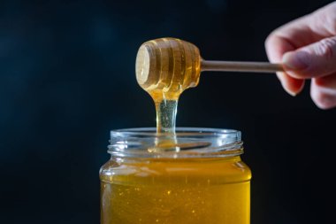 organik bal, ahşap bir kaptan cam bir kavanoza damlıyor.,