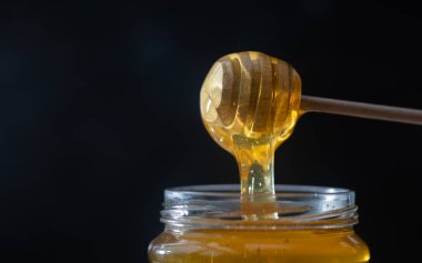 organik bal, ahşap bir kaptan cam bir kavanoza damlıyor.,