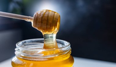 organik bal, ahşap bir kaptan cam bir kavanoza damlıyor.,