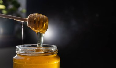 organik bal, ahşap bir kaptan cam bir kavanoza damlıyor.,