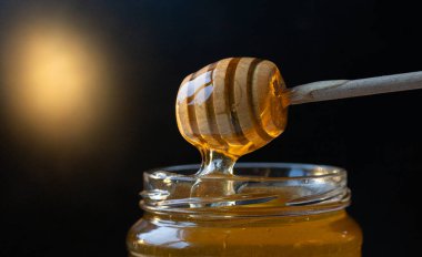 organik bal, ahşap bir kaptan cam bir kavanoza damlıyor.,