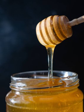 organik bal, ahşap bir kaptan cam bir kavanoza damlıyor.,