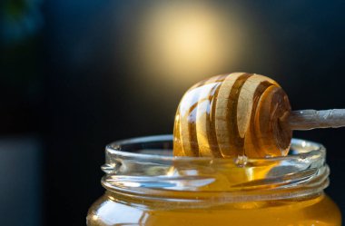 organik bal, ahşap bir kaptan cam bir kavanoza damlıyor.,