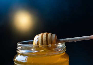 organik bal, ahşap bir kaptan cam bir kavanoza damlıyor.,