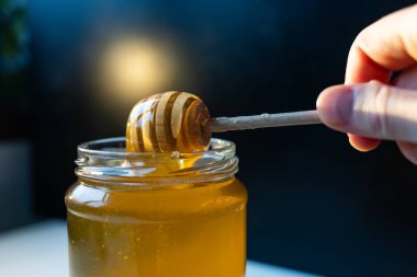 organik bal, ahşap bir kaptan cam bir kavanoza damlıyor.,