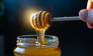 organik bal, ahşap bir kaptan cam bir kavanoza damlıyor.,