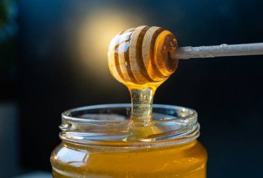 organik bal, ahşap bir kaptan cam bir kavanoza damlıyor.