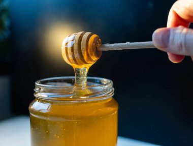 organik bal, ahşap bir kaptan cam bir kavanoza damlıyor.