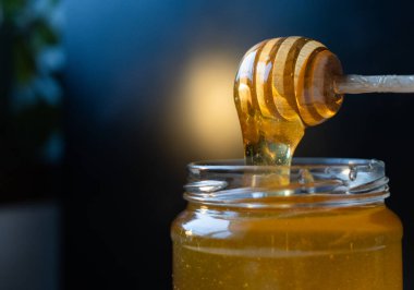 organik bal, ahşap bir kaptan cam bir kavanoza damlıyor.