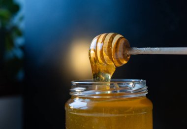 organik bal, ahşap bir kaptan cam bir kavanoza damlıyor.