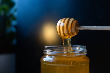 organik bal, ahşap bir kaptan cam bir kavanoza damlıyor.