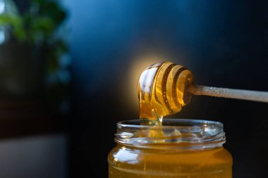 organik bal, ahşap bir kaptan cam bir kavanoza damlıyor.,