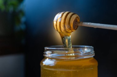 organik bal, ahşap bir kaptan cam bir kavanoza damlıyor.,