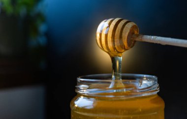 organik bal, ahşap bir kaptan cam bir kavanoza damlıyor.,